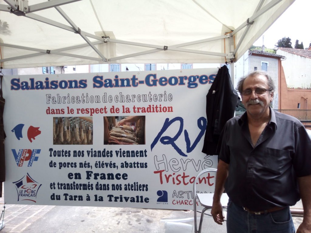 Georges Muniesa junto a la publicidad de su puesto. Saint Gervais sur Mare