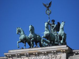 La Cuadriga, creada por Johann Gottfried Schadow, representa a la diosa de la paz Irene montada en un carro tirado por cuatro caballos en dirección a la ciudad.